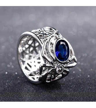 Srebrn prstan s pajkom, ki nosi modri safir